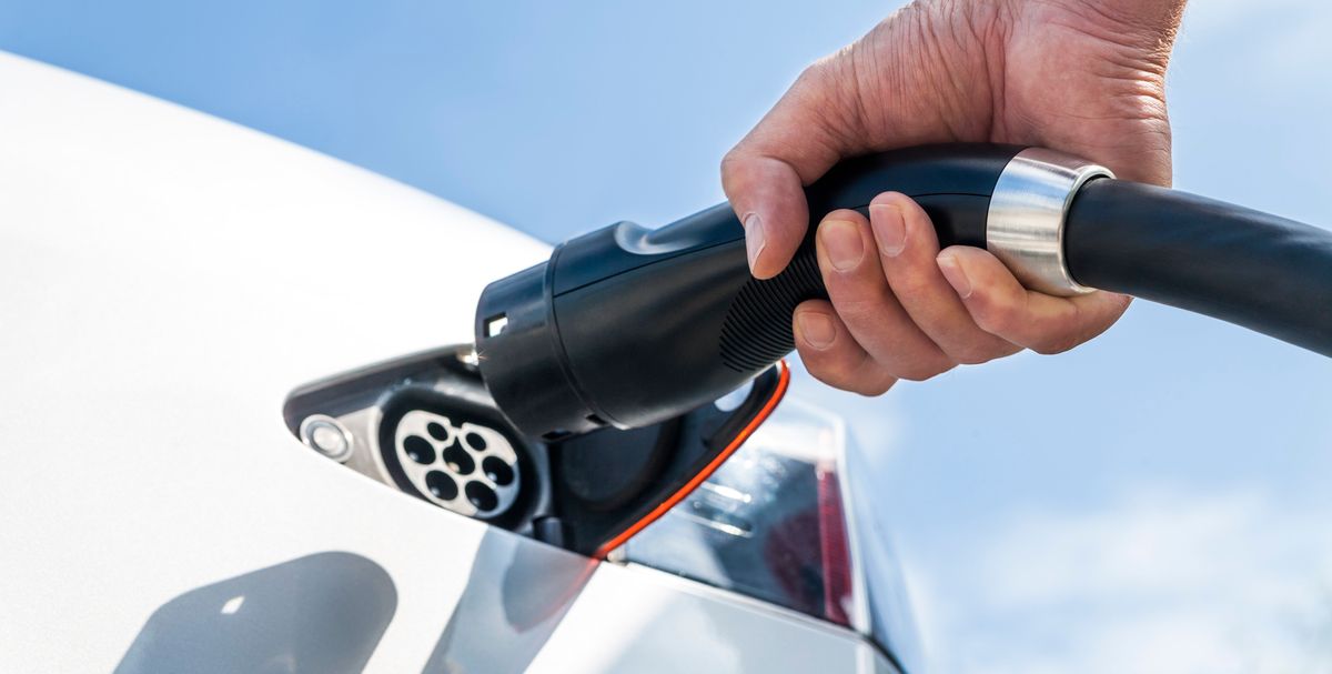 Mann steckt Supercharger-Kabel in weissen Tesla