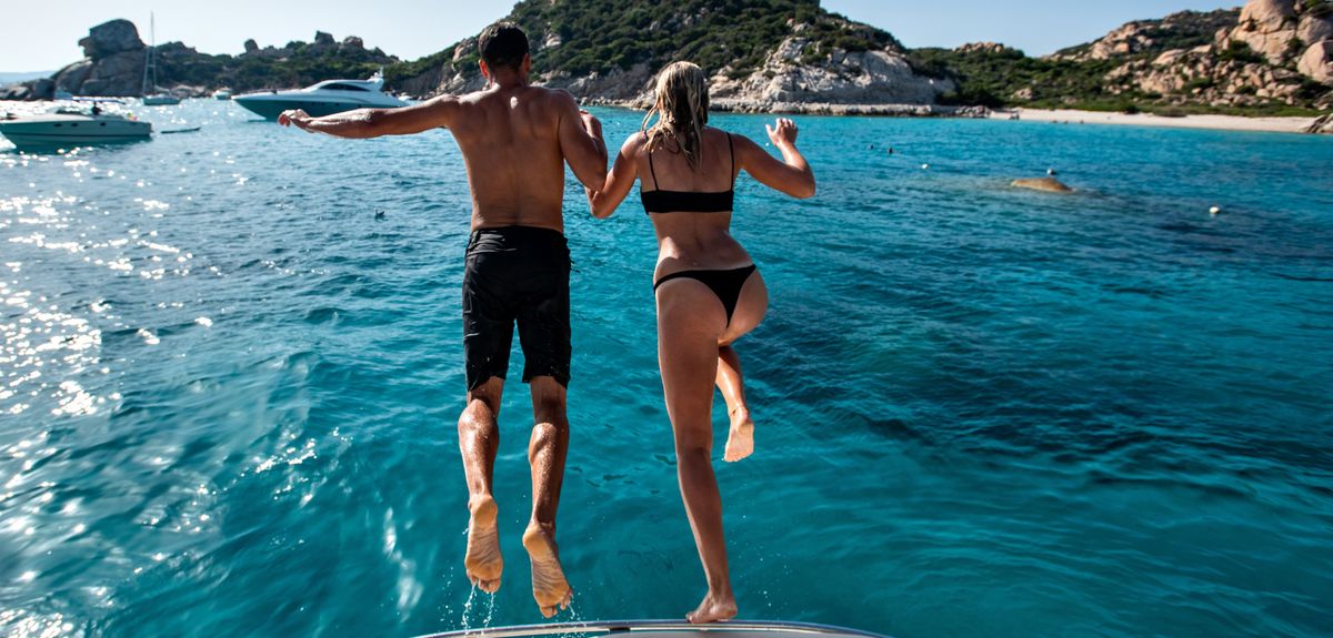 Junges Paar springt händchenhaltend ins Meer auf Sardinien